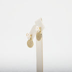 Pearl earrings with circular designs on a white stand against a white background