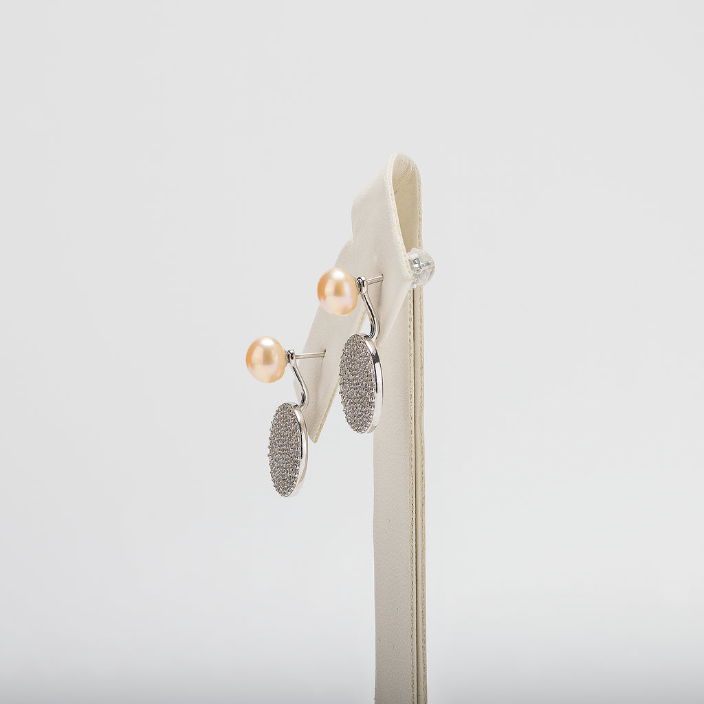 Pair of pearl earrings on a white stand against a white background