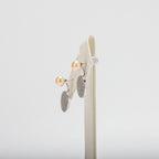 Pair of pearl earrings on a white stand against a white background