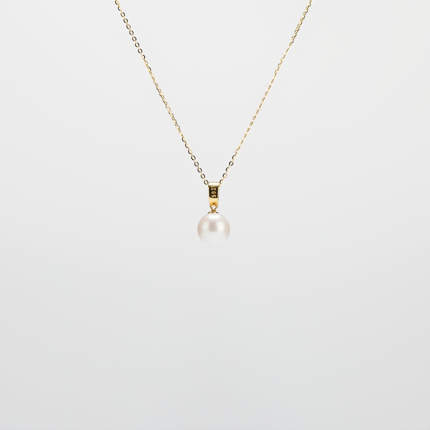 Pearl Drop Necklace with gold chain on a light gray background